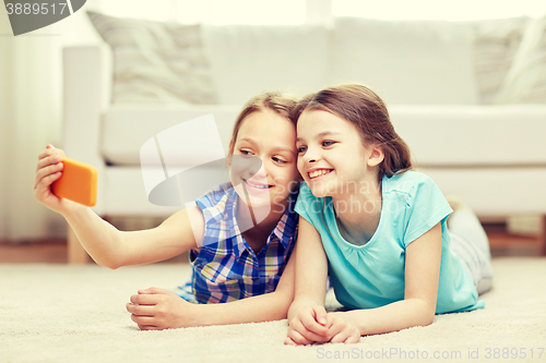 Image of happy girls with smartphone taking selfie at home