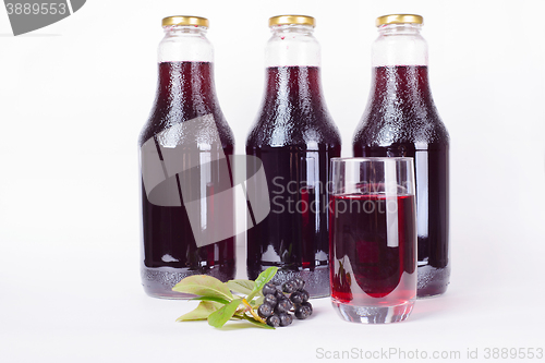 Image of Bottles of syrup made from chokeberry and glass