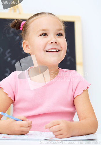 Image of Little girl is writing using a pen