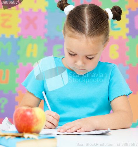 Image of Little girl is writing using a pen