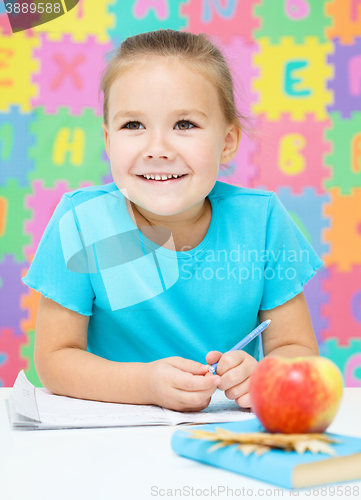 Image of Little girl is writing using a pen