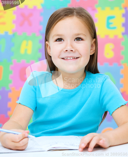 Image of Little girl is writing using a pen