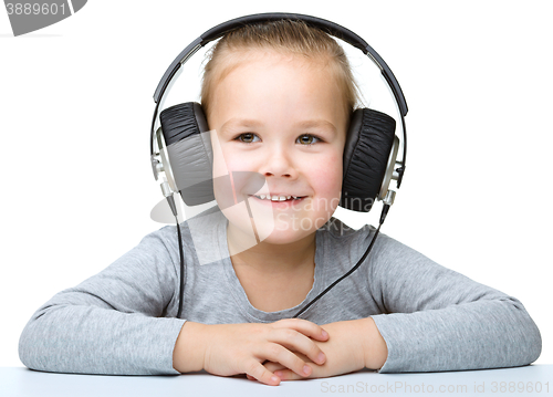 Image of Little girl is enjoying music using headphones