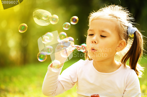 Image of Little girl is blowing a soap bubbles