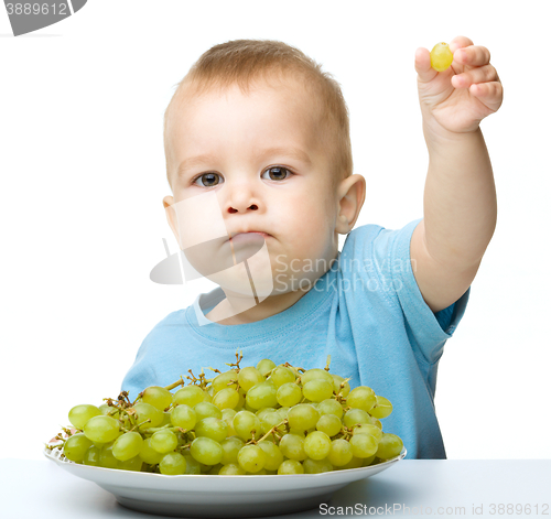 Image of Little boy is eating grapes