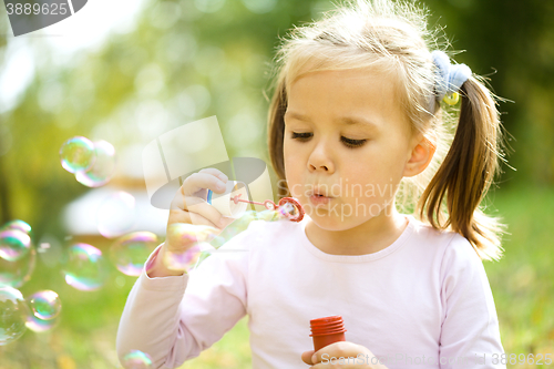 Image of Little girl is blowing a soap bubbles