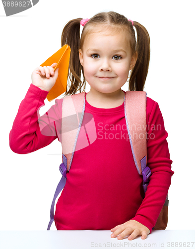 Image of Schoolgirl with backpack throwing a paper airplane