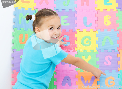 Image of Little girl is pointing at letter G on alphabet