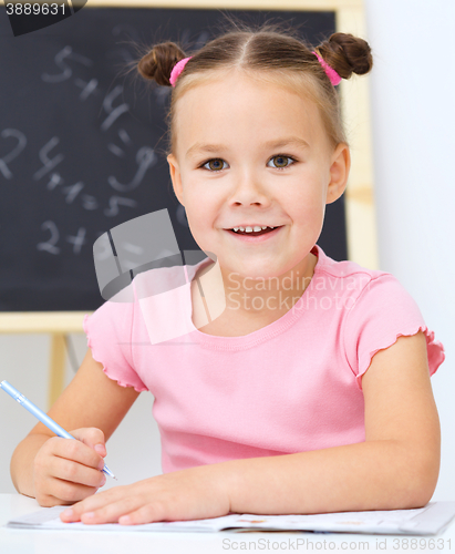 Image of Little girl is writing using a pen