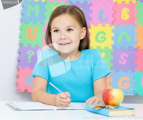 Image of Little girl is writing using a pen