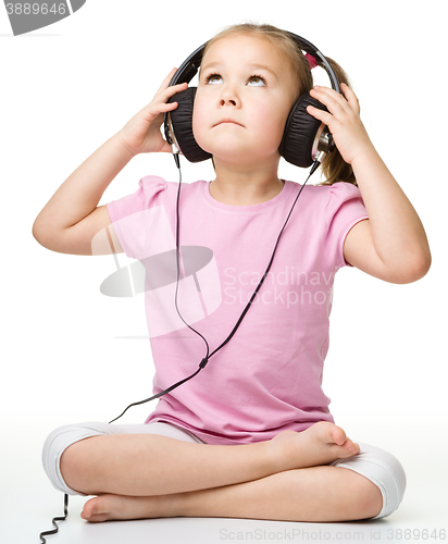 Image of Cute little girl enjoying music using headphones