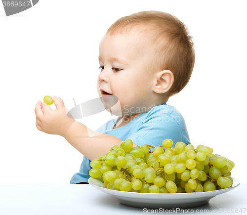 Image of Little boy is eating grapes
