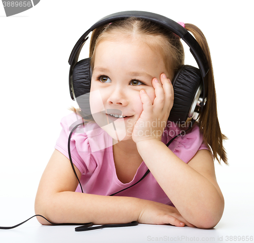 Image of Cute little girl enjoying music using headphones