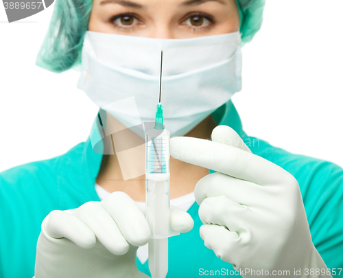 Image of Young nurse is preparing syringe for injection