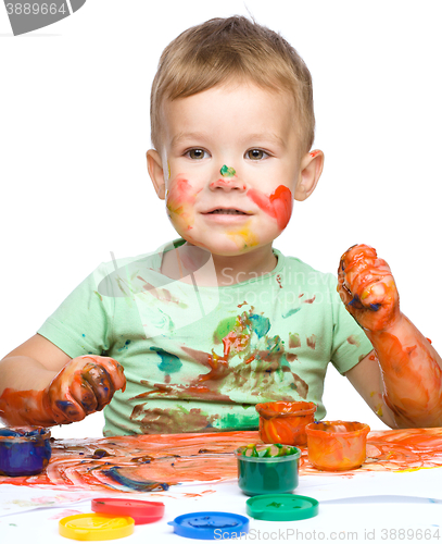 Image of Little boy is playing with paints