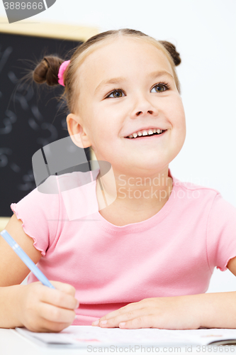 Image of Little girl is writing using a pen