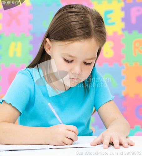 Image of Little girl is writing using a pen