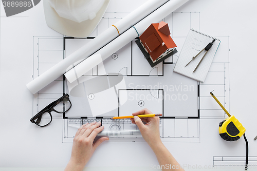 Image of close up of hands with ruler measuring blueprint