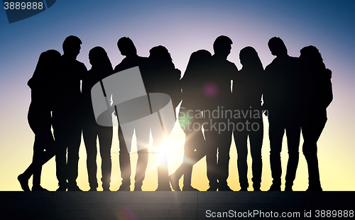 Image of silhouettes of friends sitting on stairs over sun