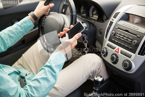 Image of close up of man with smartphone driving car