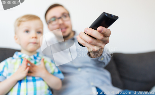 Image of father and son with remote watching tv at home