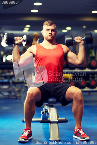 Image of young man with dumbbells flexing muscles in gym