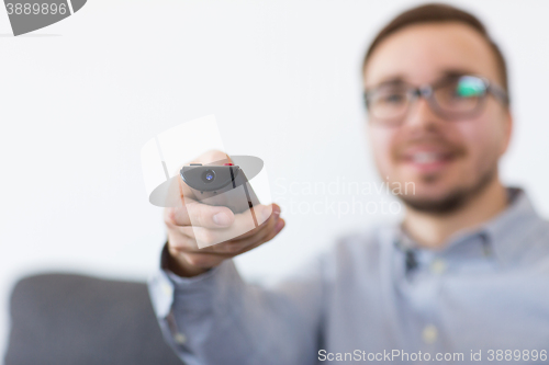 Image of smiling man with tv remote control at home