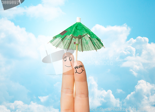 Image of close up of two fingers with cocktail umbrella