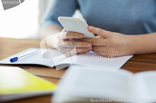 Image of close up of student with smartphone and notebook