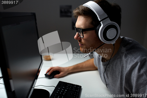 Image of man in headset playing computer video game at home