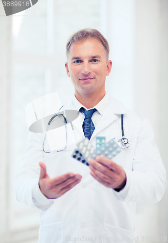 Image of young male doctor with packs of pills