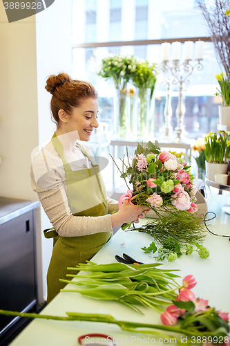 Image of smiling florist woman making bunch at flower shop