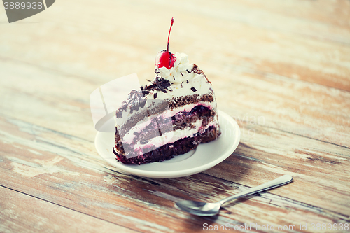 Image of piece of cherry chocolate cake on wooden table