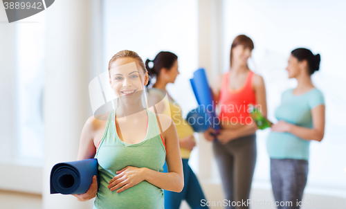 Image of happy pregnant woman with mat in gym