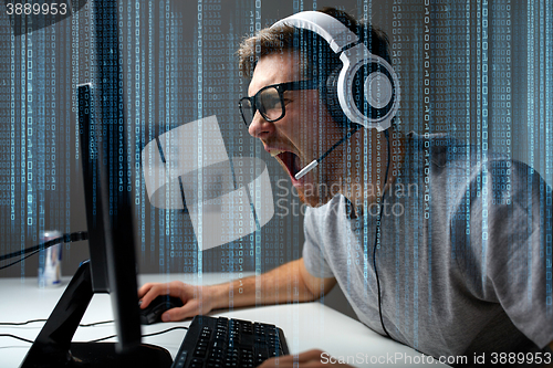 Image of man in headset playing computer video game at home