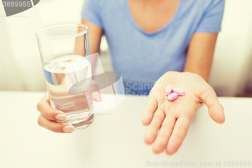 Image of close up of woman hands with pills and water
