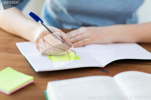 Image of close up of student with book and notebook at home