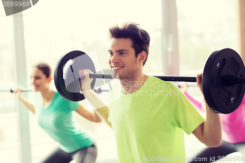 Image of group of people exercising with barbell in gym