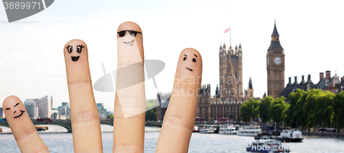 Image of close up of fingers with smiley faces over london