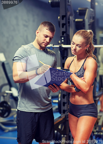 Image of young woman with personal trainer in gym