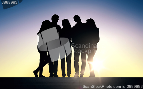 Image of silhouettes of friends sitting on stairs over sun