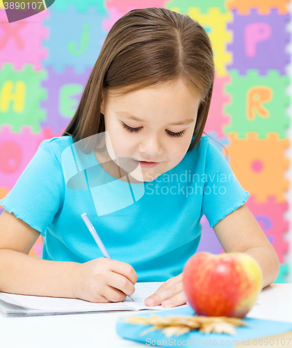 Image of Little girl is writing using a pen