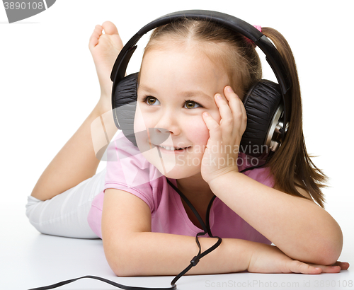 Image of Cute little girl enjoying music using headphones