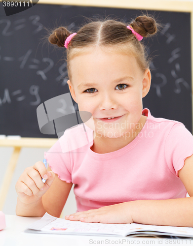 Image of Little girl is writing using a pen