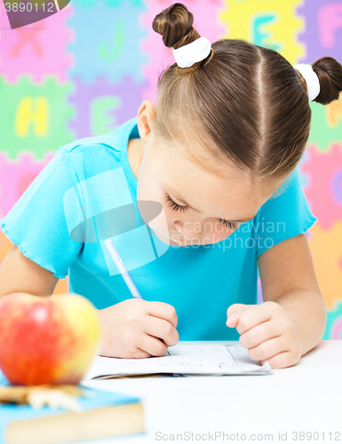 Image of Little girl is writing using a pen