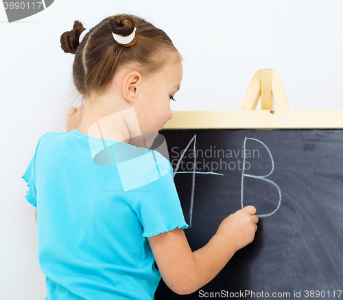 Image of Little girl is writing on a blackboard