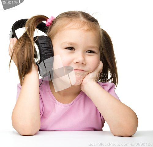Image of Cute little girl is bored to listen music