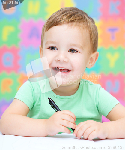 Image of Little boy is writing on his copybook