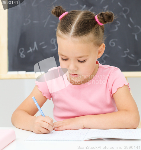 Image of Little girl is writing using a pen