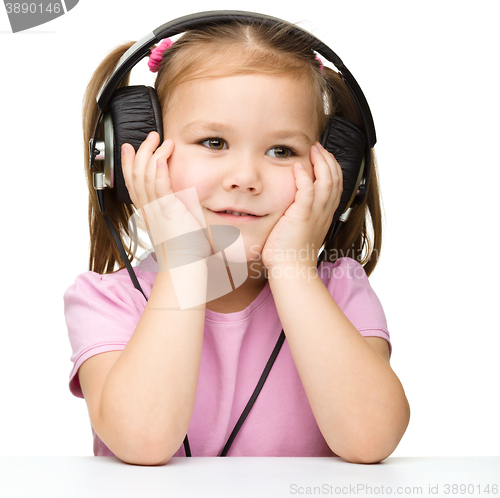 Image of Little girl is enjoying music using headphones